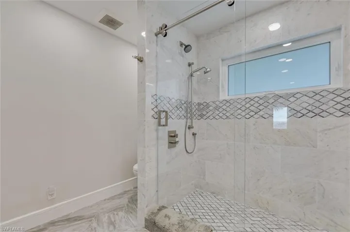 Bathroom featuring a tile shower and marble finish floors