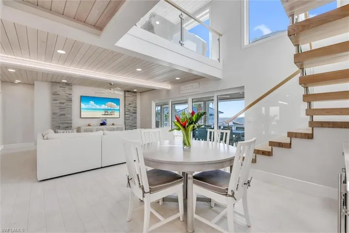 Dining area with a wooden ceiling with exposed beams, stairway, ceiling fan, wood finished floors, and a towering ceiling