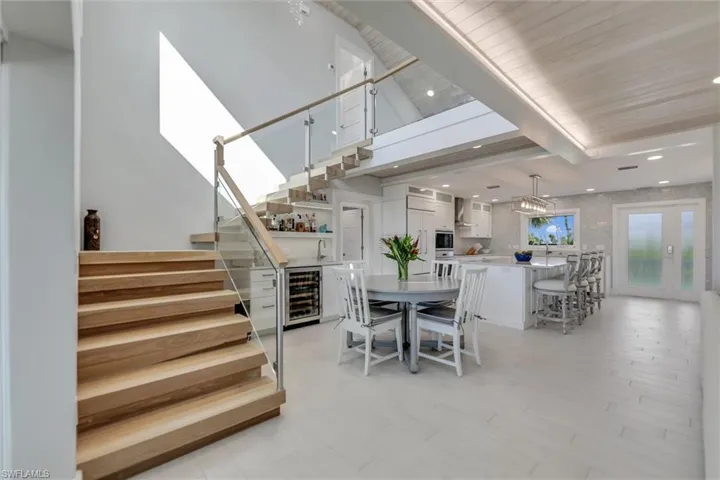 Dining room with stairway, beverage cooler, light wood-type flooring, beam ceiling, and recessed lighting