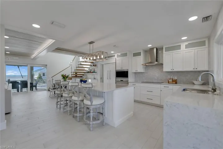Kitchen featuring light stone countertops, plenty of natural light, white cabinetry, a kitchen island, and recessed lighting
