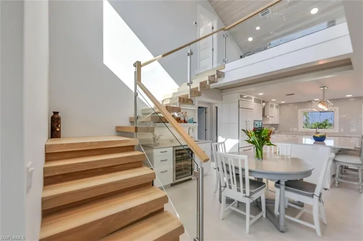 Dining area featuring stairs, a high ceiling, beverage cooler, and recessed lighting