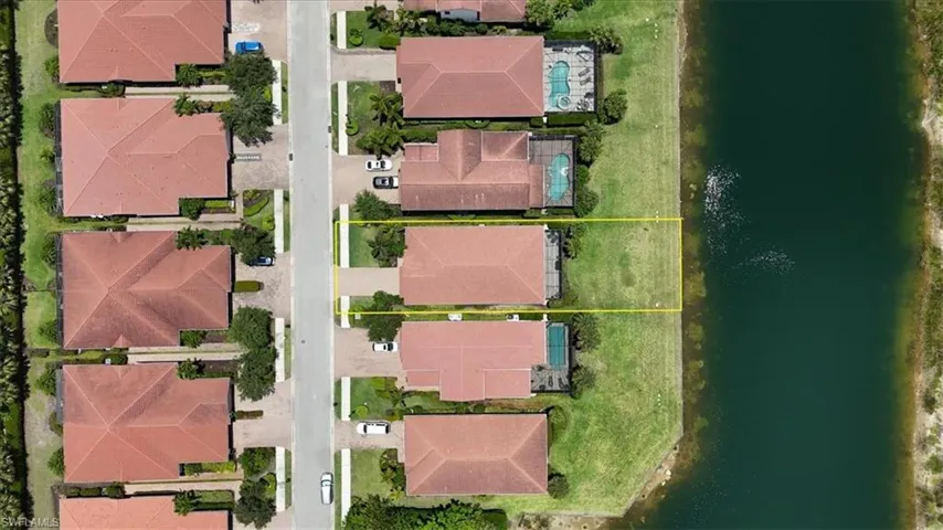 Aerial view of residential area featuring property parcel outlined and a nearby lake