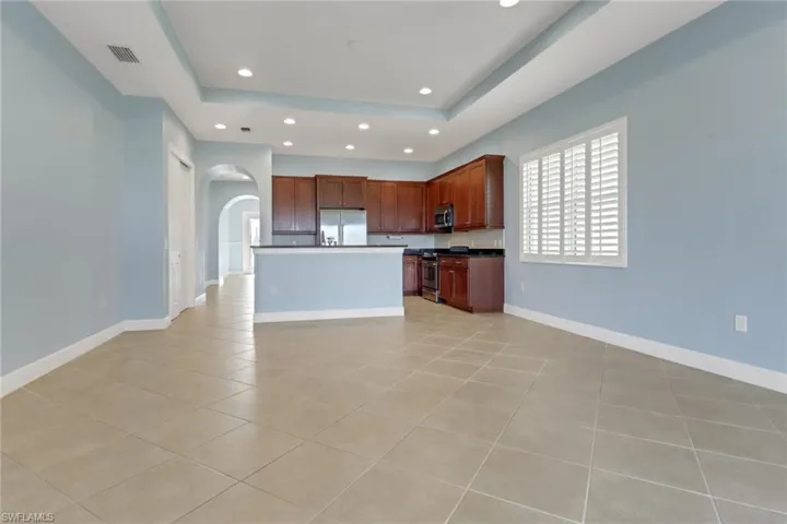 Kitchen featuring a tray ceiling, arched walkways, stainless steel appliances, granite countertops, and recessed lighting