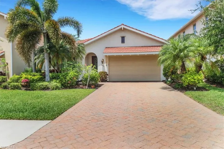 Mediterranean house featuring stucco siding, a garage, extended driveway, a front lawn, and a tiled roof