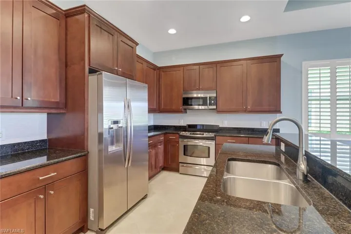 Kitchen with stainless steel appliances finishes, recessed lighting, granite  countertops, Tile flooring, and brown cabinets