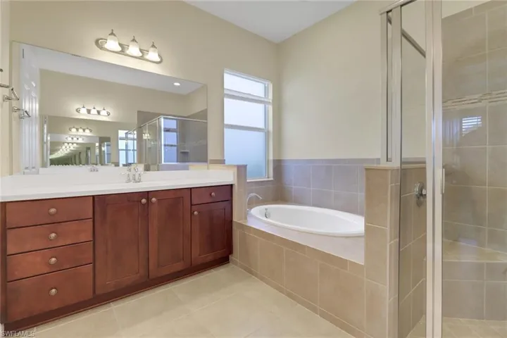 Bathroom featuring a stall shower, vanity, a garden tub, and tile patterned flooring
