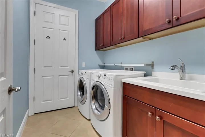 Laundry room featuring ample cabinet space, washer and dryer, and light tile flooring