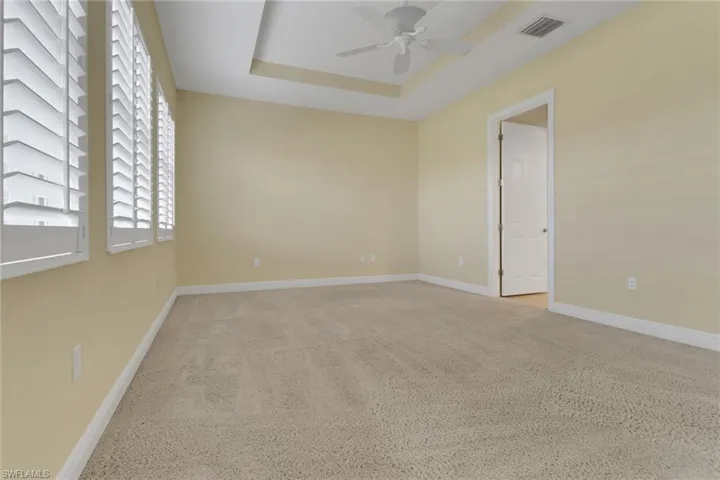 Primary bedroom with a raised ceiling, ceiling fan