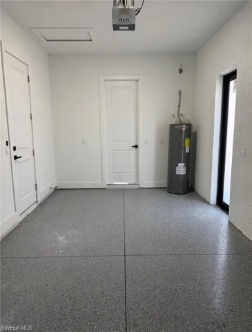 Garage interior featuring a gray speckled epoxy floor, white painted walls, and a visible water heater