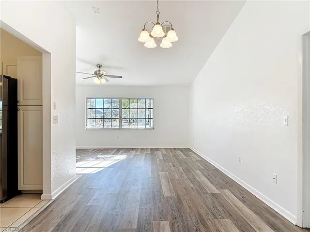 Unfurnished living room featuring suspended lighting, wood finished floors, a ceiling fan, and lofted ceiling