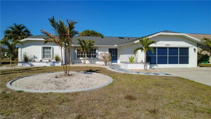 Single story home featuring a front yard, a garage, driveway, and stucco siding