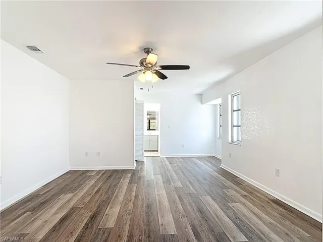 Empty room featuring dark wood-style flooring and ceiling fan
