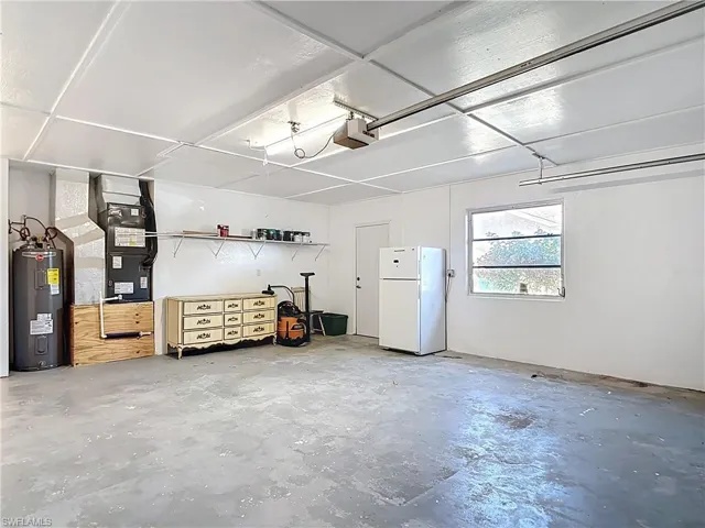 Garage featuring freestanding refrigerator, water heater, and a garage door opener