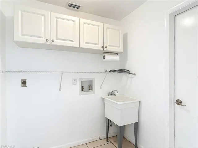Laundry room with cabinet space, hookup for a washing machine, electric dryer hookup, and light tile patterned floors