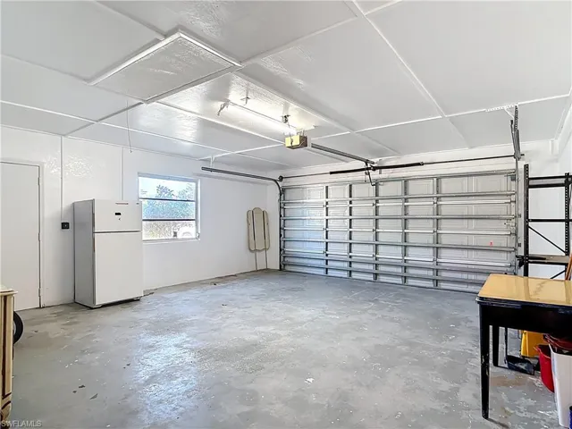 Garage featuring freestanding refrigerator and a garage door opener