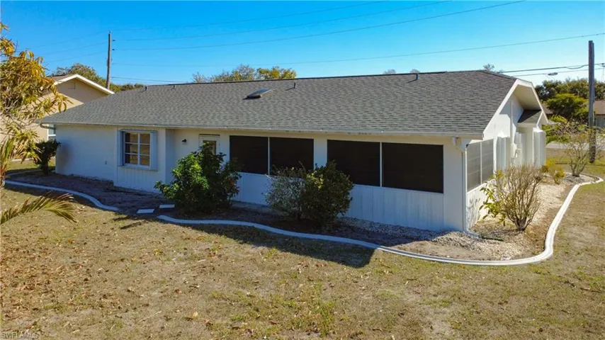 Back of house featuring a shingled roof, a yard, and a sunroom