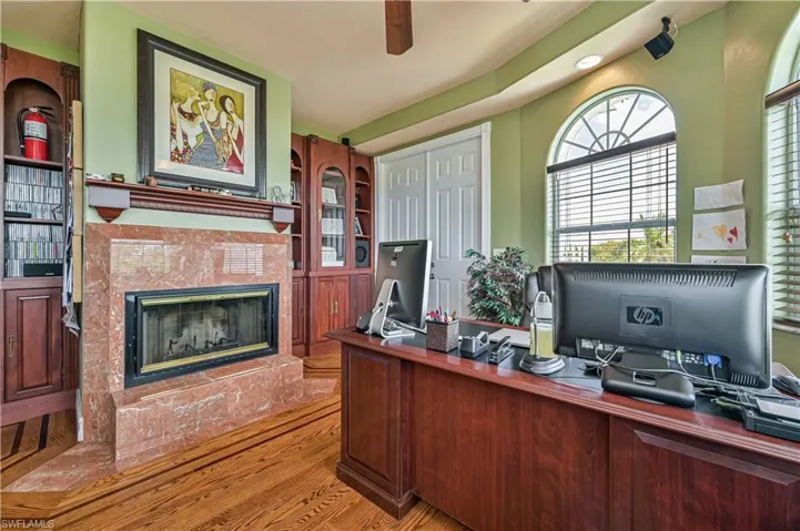 Office space with ceiling fan, wood finished floors, and a fireplace
