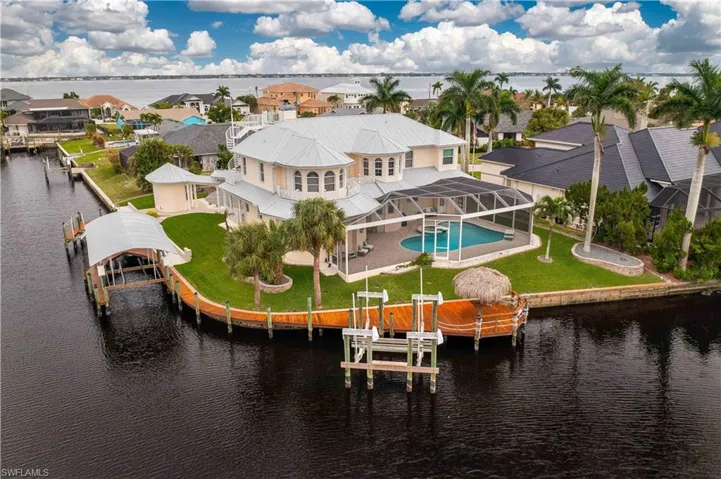 Rear view of property featuring boat lift, glass enclosure, a residential view, and a fenced in pool