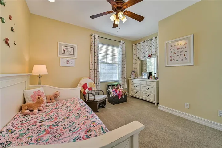 Carpeted bedroom featuring ceiling fan and baseboards