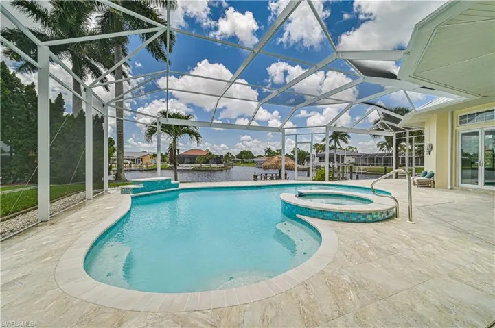 View of pool featuring glass enclosure, a pool with connected hot tub, and a patio area
