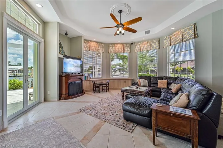 Living area featuring light tile patterned floors, a raised ceiling, a healthy amount of sunlight, and a fireplace