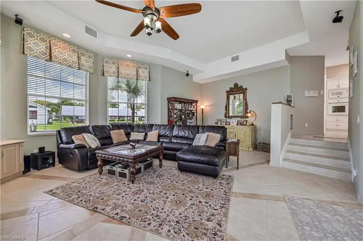 Living area with stairs, visible vents, and ceiling fan