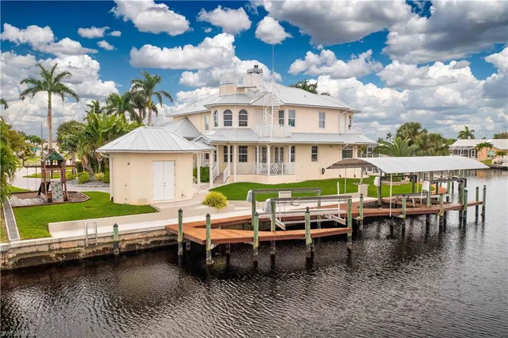 Rear view of house featuring a yard, a water view, boat lift, and metal roof