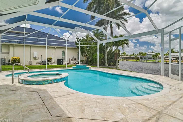 View of swimming pool with a lanai, a pool with connected hot tub, a patio, and a water view