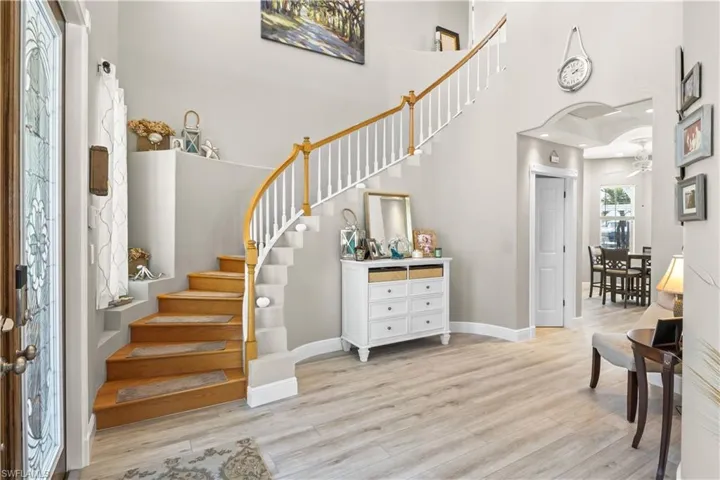 Entryway with baseboards, stairs, a high ceiling, wood finished floors, and arched walkways