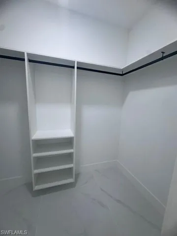 Walk in closet featuring marble look tiles