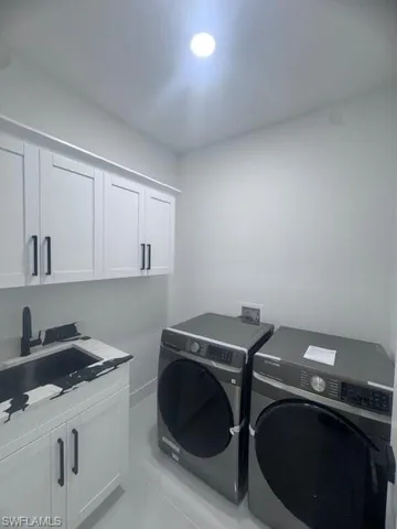 Washroom featuring separate washer and dryer and cabinet space