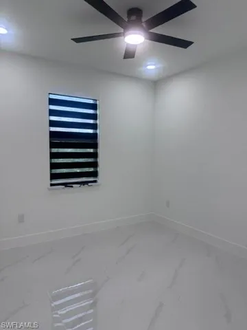 Spare room with marble look tile flooring and a ceiling fan