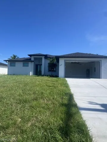 View of front of property featuring french doors, stucco siding, an attached garage, driveway, and a front lawn