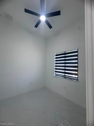 Unfurnished room with marble look tiles and a ceiling fan