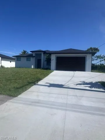 Prairie-style house featuring concrete driveway, a garage, a front yard, and stucco siding