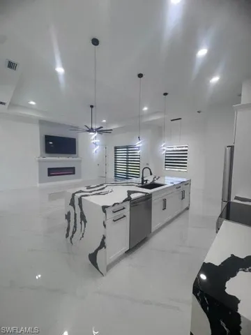 Kitchen featuring light marble finish floors, white cabinetry, light stone countertops, pendant lighting, and recessed lighting