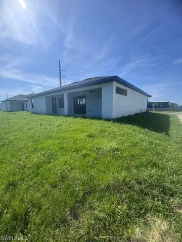 Rear view of property with a lawn and stucco siding