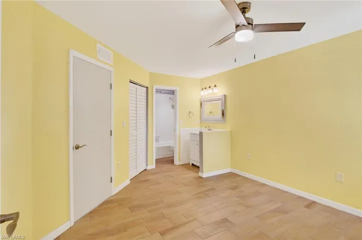 Unfurnished bedroom featuring a barn door, light wood-type flooring, a ceiling fan, and a closet