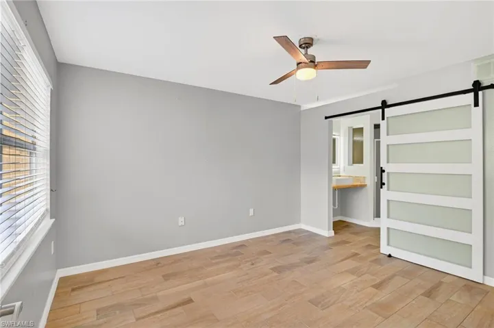 Unfurnished bedroom with ceiling fan, light wood-style floors, a closet, and connected bathroom