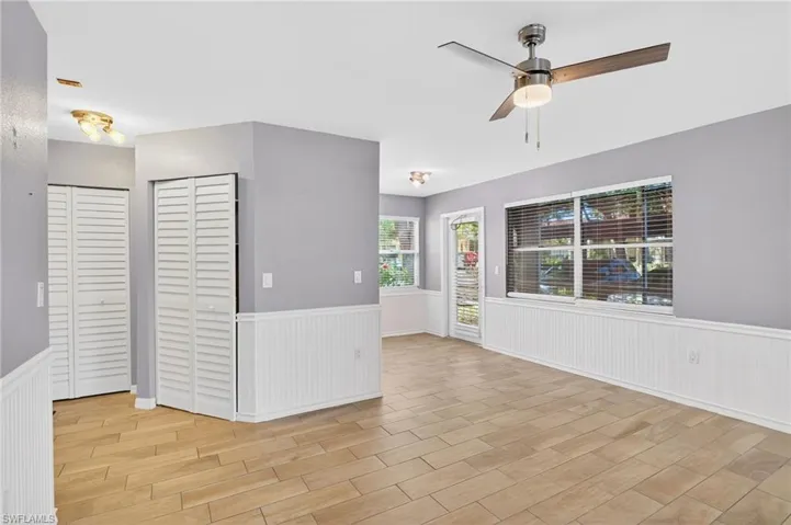 Unfurnished dining area with light wood-type flooring, a chandelier, plenty of natural light, and a wainscoted wall