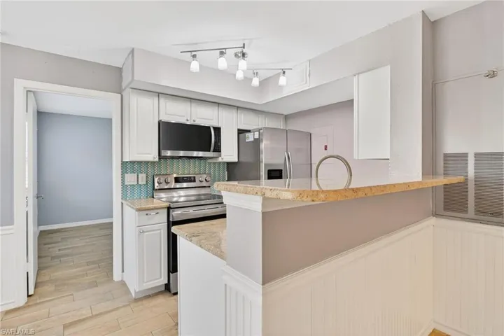 Laundry room with water heater, a textured wall, and washer and clothes dryer