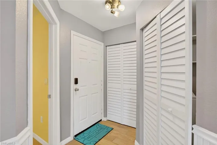 Kitchen with stainless steel appliances, white cabinets, light stone counters, and light wood-type flooring