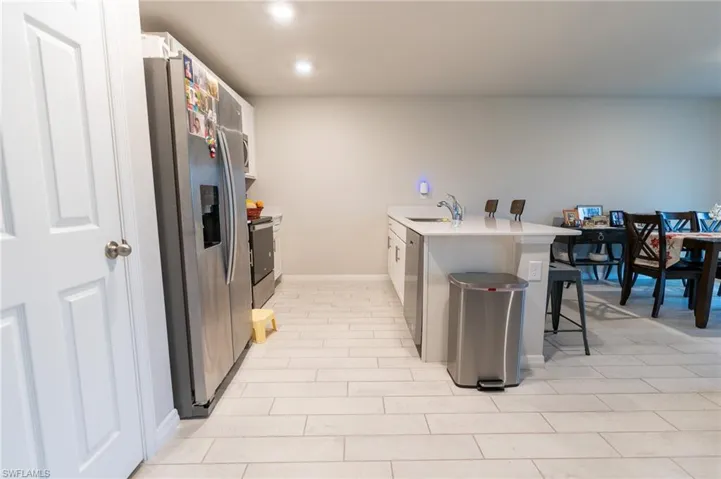 Kitchen featuring sink, white cabinetry, a kitchen bar, appliances with stainless steel finishes, and light tile patterned floors