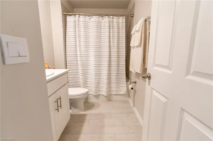 Full bathroom with shower / bath combo with shower curtain, tile patterned floors, vanity, and toilet