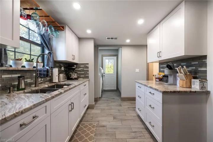 Kitchen featuring a sink, recessed lighting, tasteful backsplash, white cabinetry, and light wood-style floors