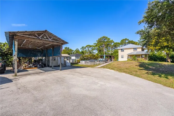 View of parking / parking lot featuring a carport and driveway