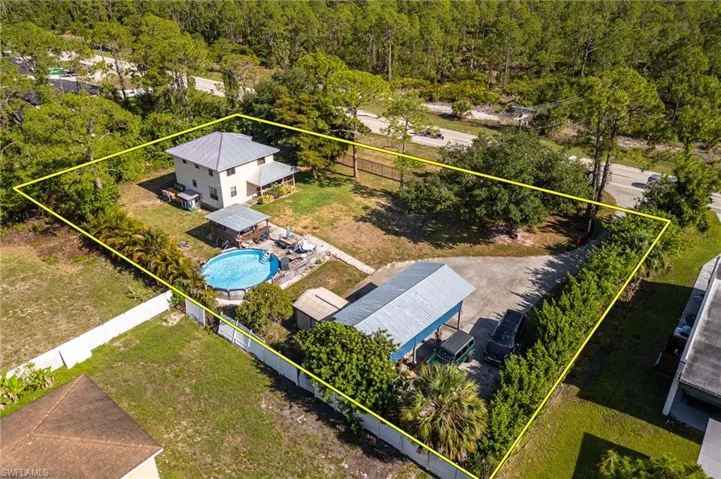 View from above of property featuring property parcel outlined, a forest, and a pool