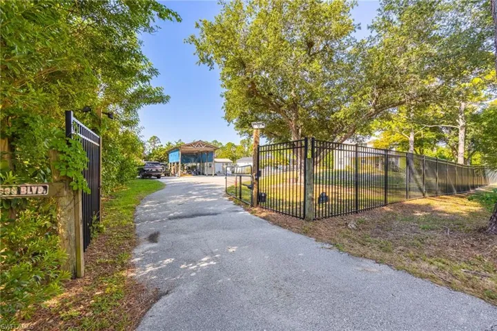 View of asphalt driveway with a gated entry