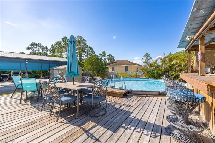 Wooden terrace featuring an outdoor pool and outdoor dining area