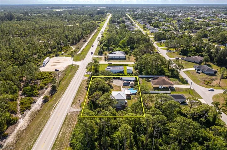 Aerial view of residential area with property boundaries highlighted and a highway
